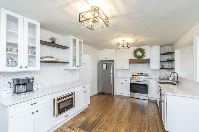 kitchen featuring open shelves, dark wood-type flooring, light countertops, appliances with stainless steel finishes, and a sink