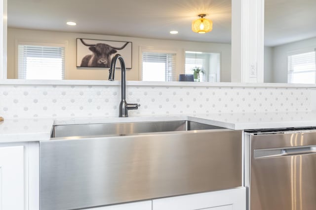 kitchen with decorative backsplash, dishwasher, white cabinets, and light countertops