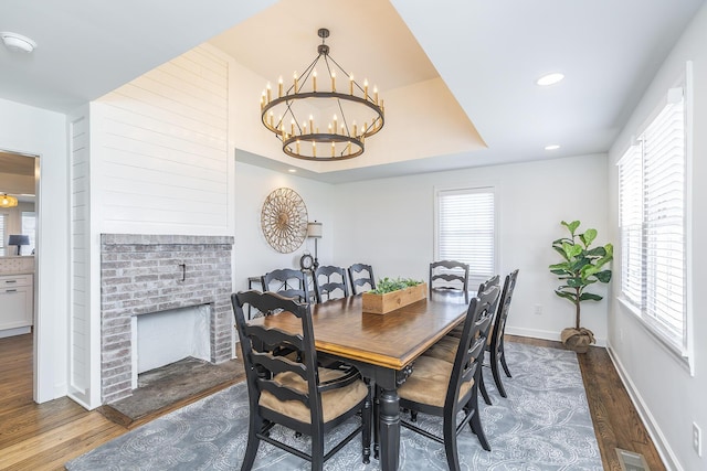 dining area featuring a fireplace, wood finished floors, a healthy amount of sunlight, and baseboards