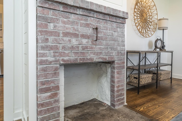 details featuring a brick fireplace, baseboards, and wood finished floors