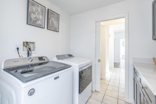 laundry area with washer and dryer, light tile patterned floors, and cabinet space