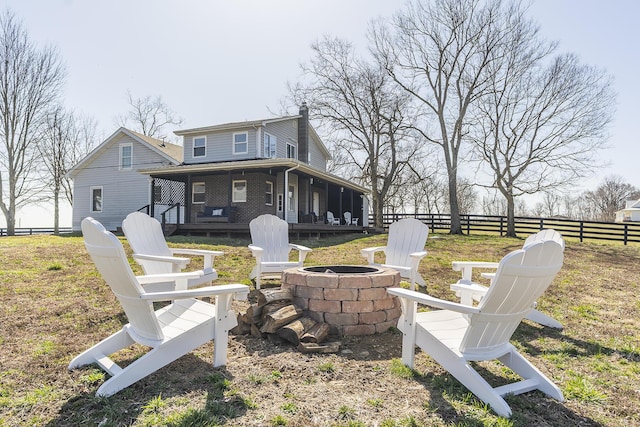 back of property with fence, brick siding, and an outdoor fire pit