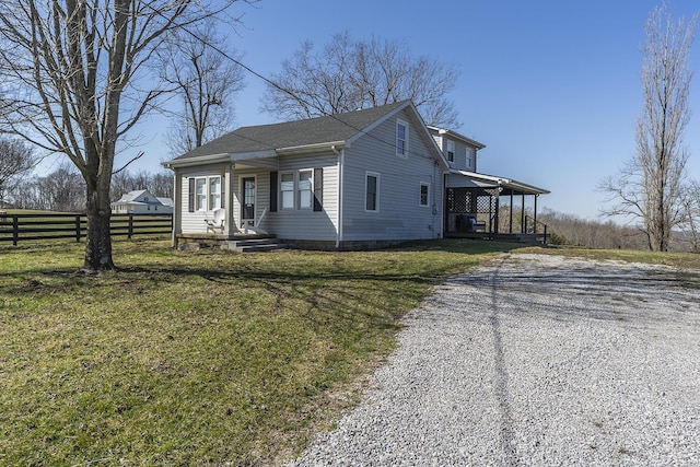 view of front of property featuring gravel driveway, a front yard, and fence