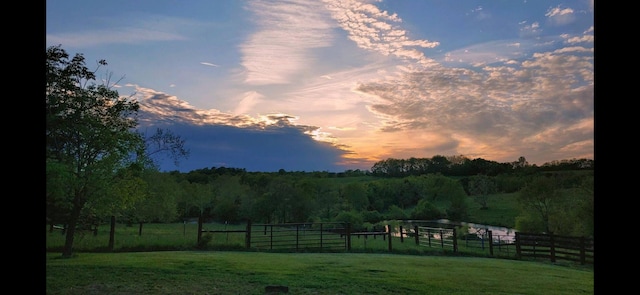 yard at dusk with a rural view and fence