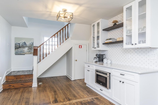 kitchen with oven, light countertops, decorative backsplash, dark wood-style floors, and open shelves