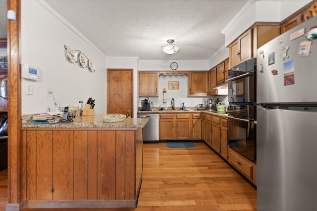 kitchen with brown cabinetry, light wood-type flooring, appliances with stainless steel finishes, and ornamental molding