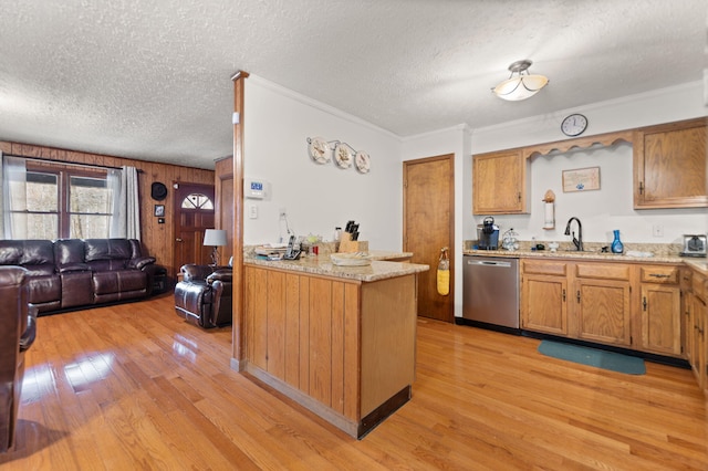 kitchen featuring brown cabinets, a sink, stainless steel dishwasher, open floor plan, and light wood-style floors