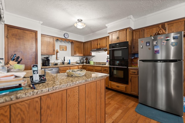 kitchen featuring brown cabinetry, black appliances, under cabinet range hood, crown molding, and light wood-type flooring