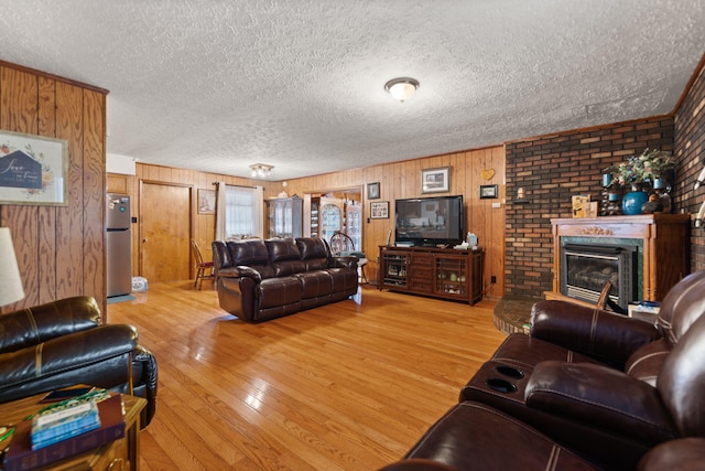 living area with wood-type flooring, a textured ceiling, and a brick fireplace