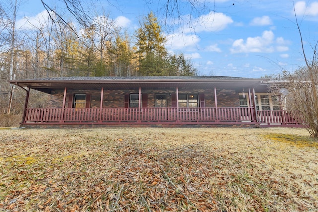 view of front of house featuring a front yard, brick siding, and covered porch