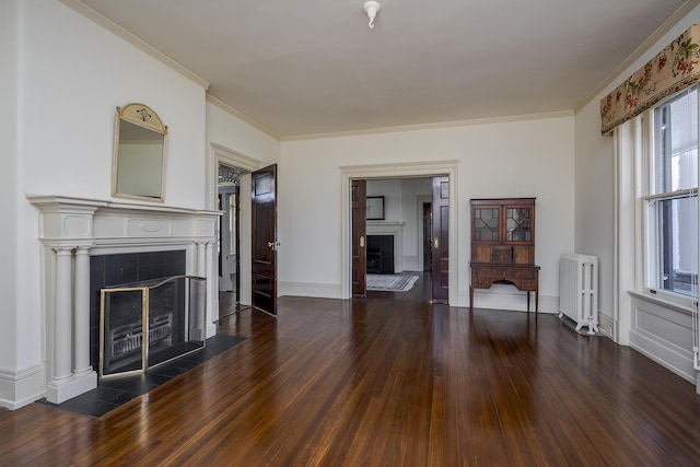 unfurnished living room with a tiled fireplace, crown molding, radiator heating unit, and wood finished floors