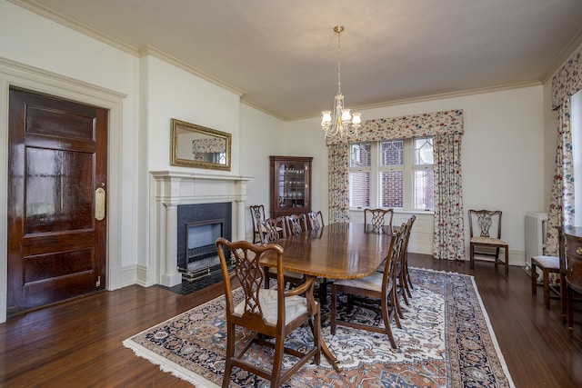 dining room with an inviting chandelier, crown molding, a fireplace with flush hearth, and wood finished floors