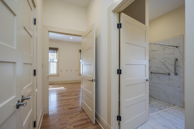 hall featuring light wood-style flooring and baseboards