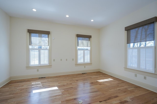 spare room featuring plenty of natural light, wood finished floors, and visible vents