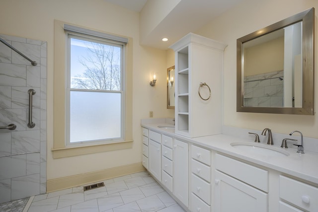 full bathroom featuring a tile shower, visible vents, double vanity, and a sink