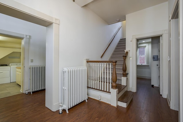 staircase with washer and dryer, baseboards, wood finished floors, and radiator heating unit