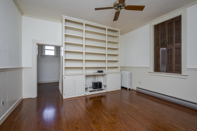 unfurnished living room with radiator, ceiling fan, dark wood-type flooring, wainscoting, and crown molding