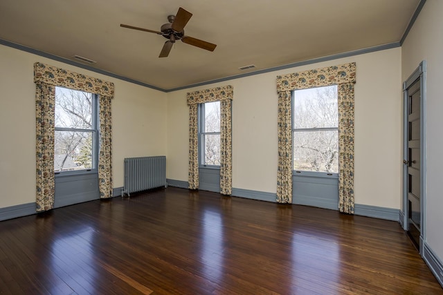 empty room with visible vents, radiator, crown molding, and wood finished floors