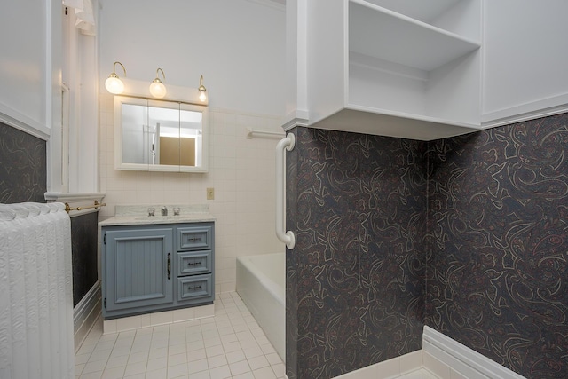 full bathroom featuring tile patterned floors, tile walls, a tub, and vanity