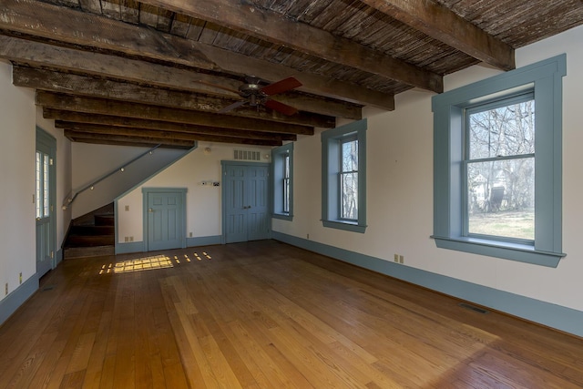 unfurnished living room with baseboards, ceiling fan, beamed ceiling, stairs, and wood-type flooring