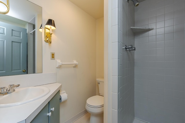 bathroom featuring vanity, baseboards, tiled shower, tile patterned floors, and toilet