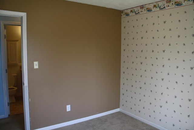 carpeted spare room featuring baseboards