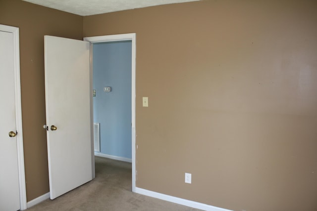 unfurnished bedroom with light carpet, visible vents, and baseboards