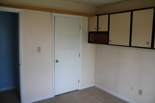 interior space featuring baseboards and light carpet