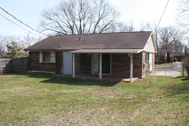 rear view of house featuring a lawn, a patio, fence, roof with shingles, and brick siding