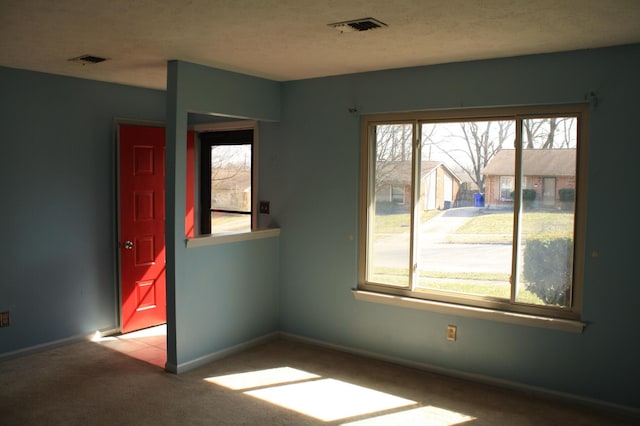 empty room with baseboards, visible vents, carpet floors, and a textured ceiling