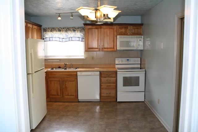 kitchen with brown cabinetry, white appliances, and a sink