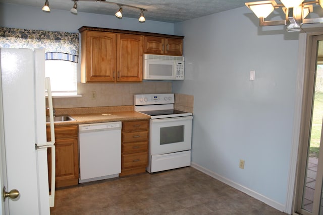 kitchen featuring tasteful backsplash, baseboards, light countertops, brown cabinets, and white appliances