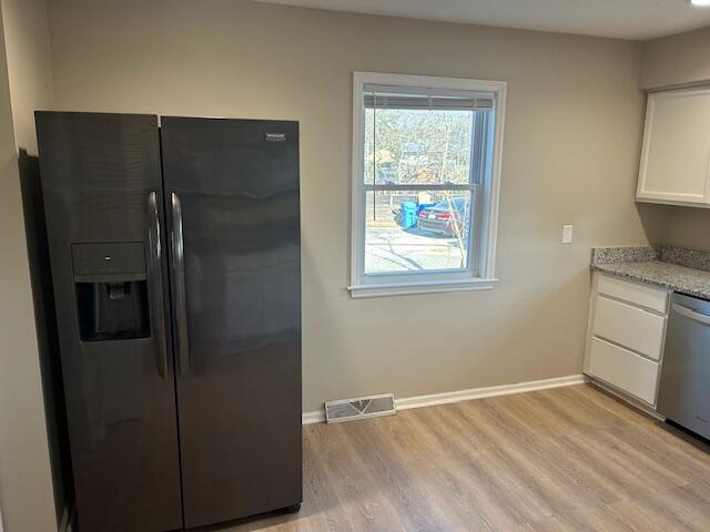 kitchen featuring visible vents, white cabinetry, light wood-style flooring, black fridge with ice dispenser, and stainless steel dishwasher