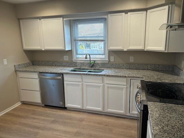 kitchen featuring a sink, light wood-style floors, appliances with stainless steel finishes, white cabinetry, and wall chimney exhaust hood