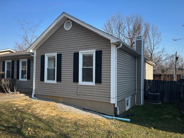 view of side of home with a chimney, a yard, and fence