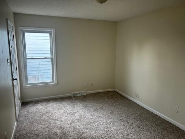 carpeted spare room with visible vents and baseboards