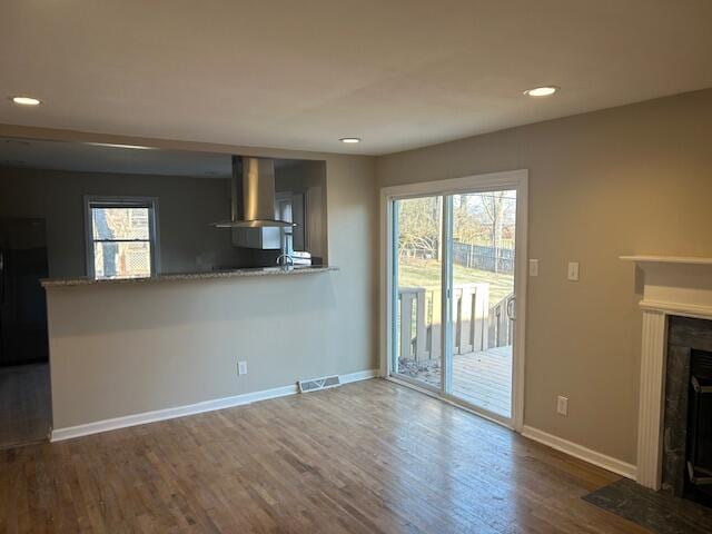 unfurnished living room with a fireplace with flush hearth, plenty of natural light, baseboards, and wood finished floors