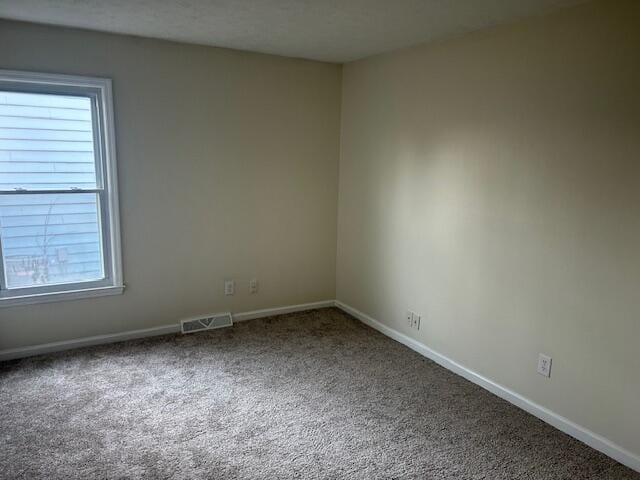 empty room with visible vents, baseboards, and carpet floors