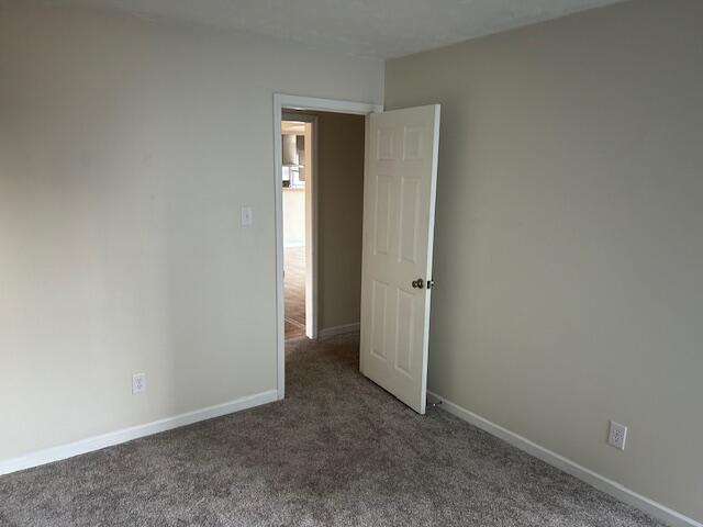 carpeted empty room featuring baseboards