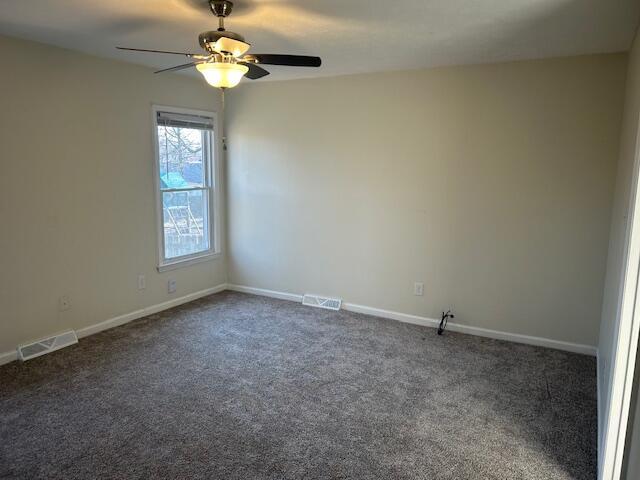 empty room featuring visible vents, baseboards, and dark colored carpet