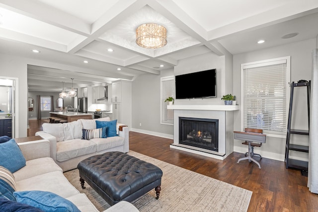 living area with dark wood finished floors, a notable chandelier, coffered ceiling, and baseboards