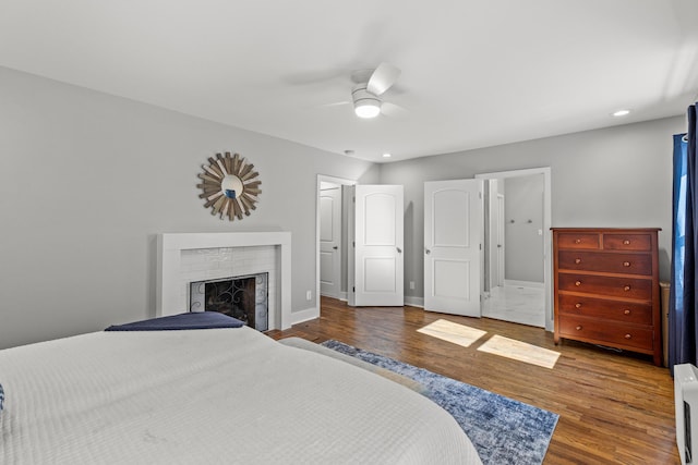 bedroom featuring wood finished floors, recessed lighting, baseboards, a brick fireplace, and ceiling fan