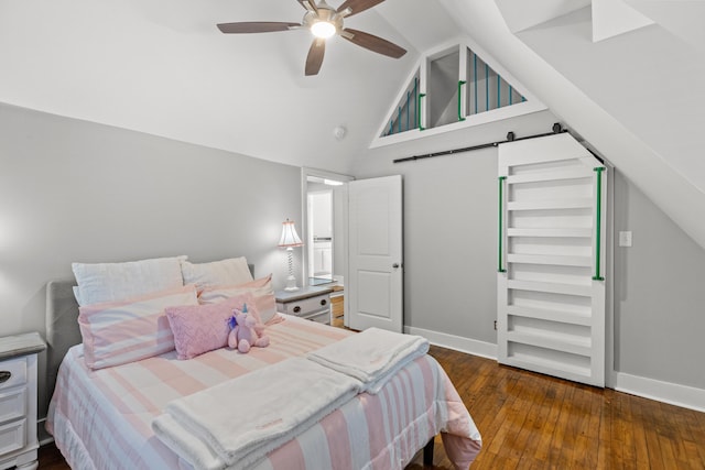 bedroom featuring baseboards, wood-type flooring, a ceiling fan, and a barn door