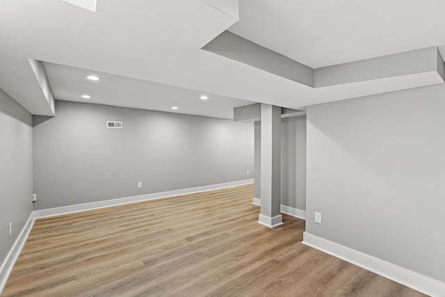 finished basement with light wood-style flooring, recessed lighting, visible vents, and baseboards