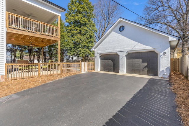 exterior space featuring a detached garage, fence, an outbuilding, and brick siding