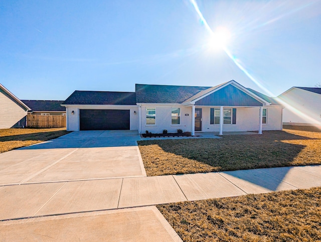 ranch-style home featuring an attached garage, concrete driveway, a front lawn, and fence