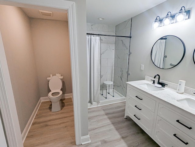 full bath featuring a sink, toilet, a stall shower, and wood finished floors