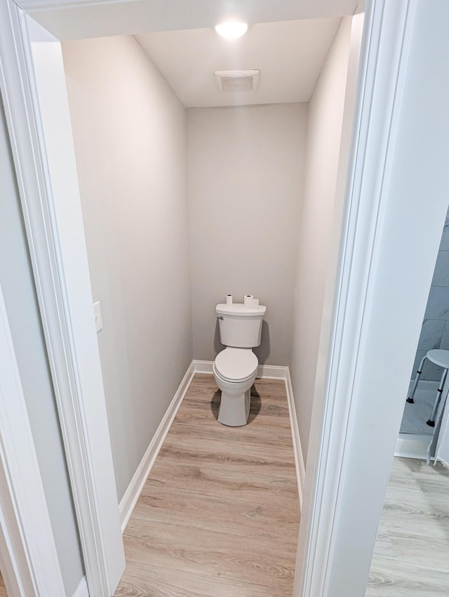 bathroom with toilet, wood finished floors, and baseboards