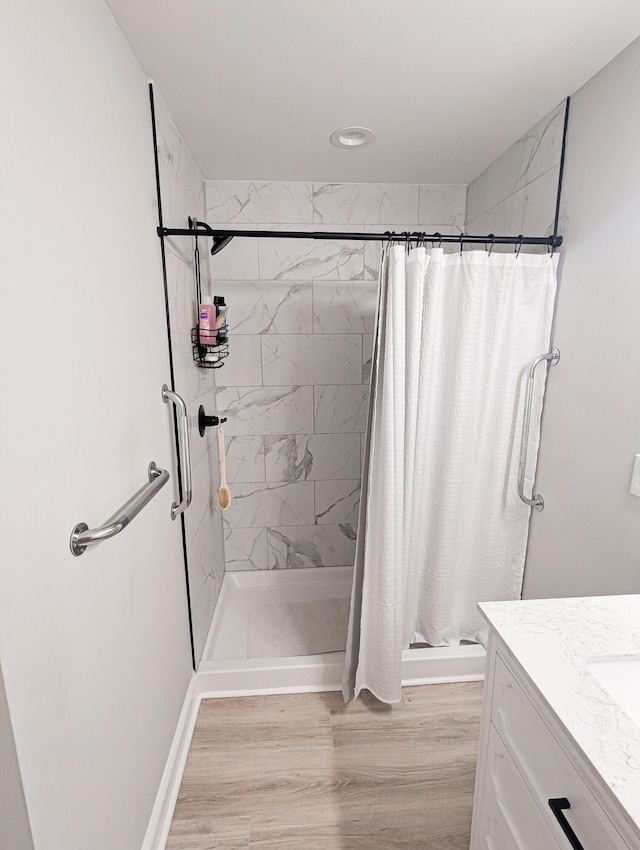 bathroom featuring a stall shower, vanity, baseboards, and wood finished floors