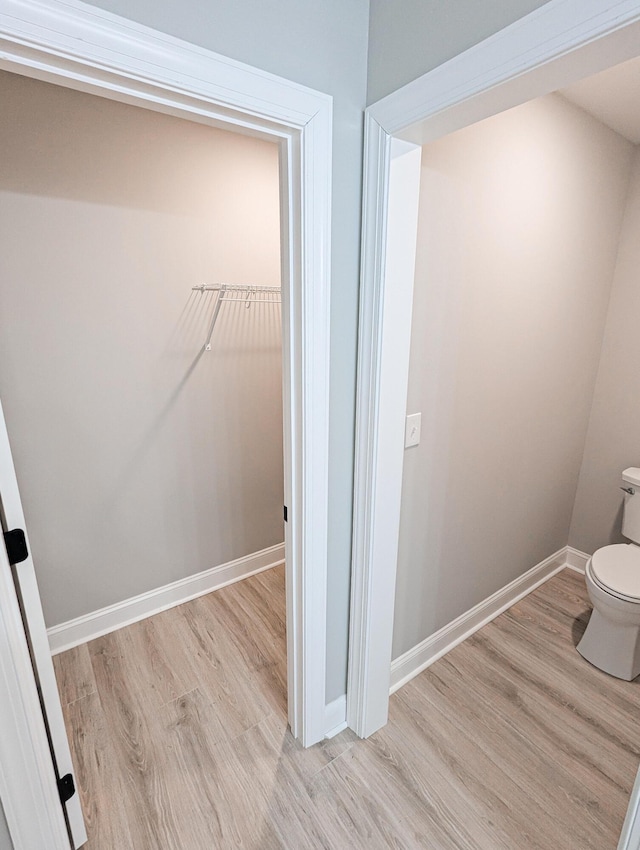 bathroom with baseboards, toilet, and wood finished floors